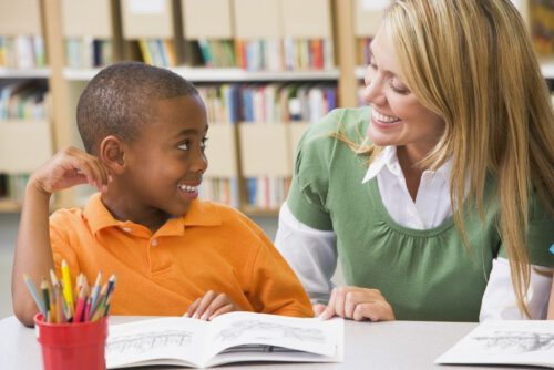 Kindergarten teacher helping student with reading skills